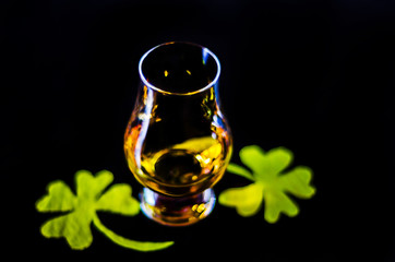 Single malt whiskey in a glass of tasting with decoration for St. Patrick's day, green clover...
