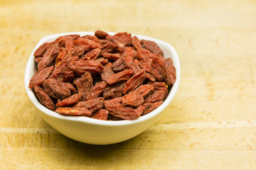 Dried goji berries on a wooden board.