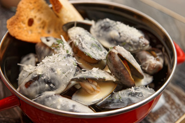 Mussels cooked with creamy sauce and served in metal pot