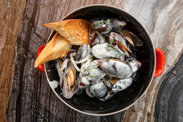 Mussels cooked with creamy sauce and served in metal pot