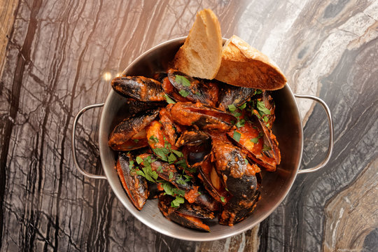Mussels cooked with arrabiata sauce and served in metal pot