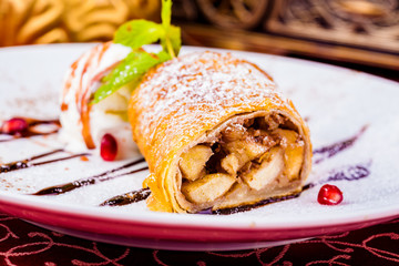 Strudel with apple and ice cream on white plate