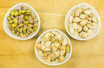 Top view of a bowl with pistachios in a shell, shell and a shelled nut.