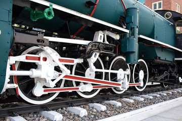 An old steam locomotive in black and green color is shown in the park for people to take a look. 