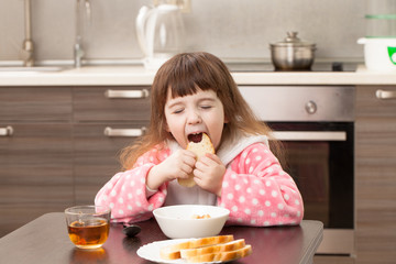 Girl in the kitchen at the table. Childhood.