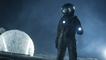 Courageous Astronaut in the Space Suit Holds Flashlight and Explores Misty Alien Planet. In the Background Living Habitat. Space Travel, Habitable World and Colonization Concept. - obrazy, fototapety, plakaty