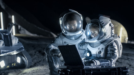 Two Astronauts Wearing Space Suits Work on a Laptop, Exploring Newly Discovered Planet, Send...