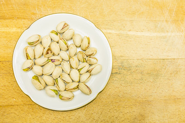Plate with roasted pistachios in shell. View from above.