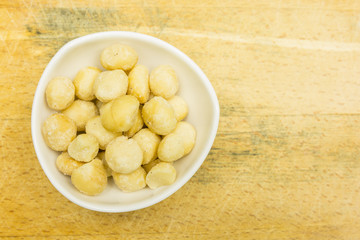 Bowl with roasted and salted macadamia nuts. View from above.