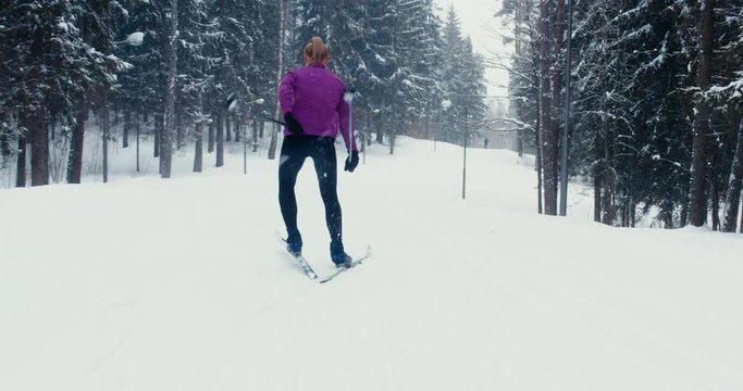 TRACKING Young adult Caucasian female athlete practicing cross-country skiing on a scenic forest trail. 4K UHD 60 FPS SLO MO