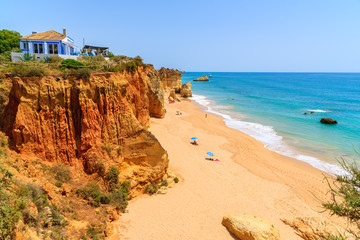House of top of a cliff and view of beautiful beach with rocks near Portimao town, Algarve, Portugal