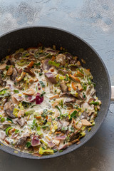 Trofie pasta with muschrooms leek and creme fraiche. Pan on blue and gray background. 
