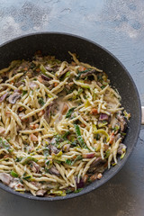 Trofie pasta with muschrooms leek and creme fraiche. Pan on blue and gray background. 
