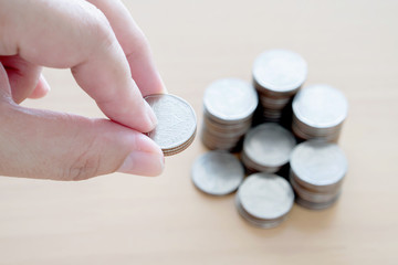 Hand giving coins into stack.
