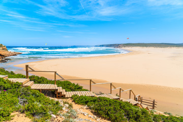 Naklejka premium Wooden walkway to beautiful Praia da Bordeira beach, popular place to do kite surfing, Algarve, Portugal