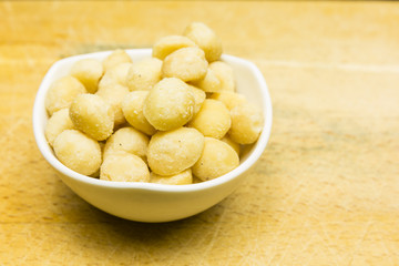 Bowl with roasted and salted macadamia nuts.