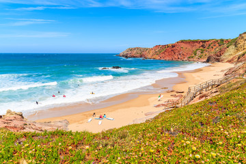 Surfers on beautiful Praia do Amado beach, popular place to do water sports, Algarve, Portugal - obrazy, fototapety, plakaty