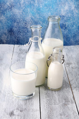 A jug of milk and glass of milk on a wooden table.
