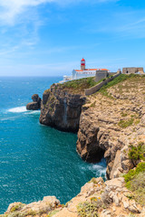 Fototapeta na wymiar Blue sea and lighthouse on top of cliff at Cabo Sao Vicente, Algarve region, Portugal