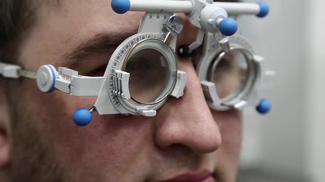 Man patient at the reception of an ophthalmologist, selection of spectacle lenses in ophthalmology clinic, man face close-up