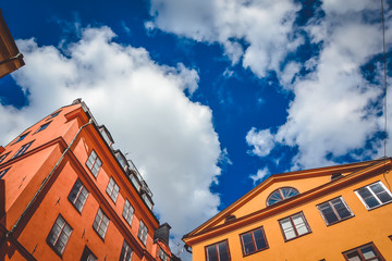 Fototapeta na wymiar Orange and red building with many windows in the city of Stockholm, Sweden on a sunny summer day against a background of cloudy and contrasting sky