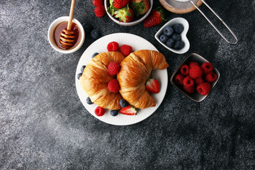 Fototapeta na wymiar Delicious breakfast with fresh croissants and ripe berries on old marble background