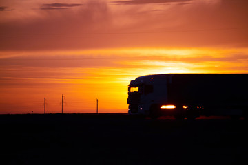 Silhouette of a moving truck at sunset. A truck is a motor vehicle designed to transport cargo. Trucks vary greatly in size, power, and configuration.