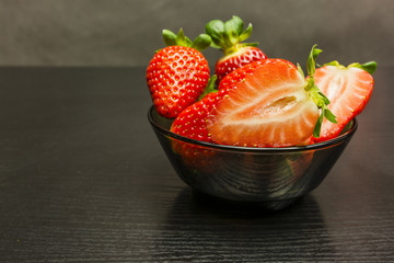 Bowl with red ripe strawberries on a wooden background.
