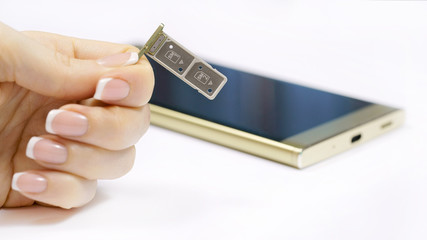 a female hand holds a dual SIM card slot. Nano SIM and memory card with ejector pin and tray for Touchscreen phone