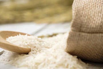 A wooden spoon filled with rice placed on wooden background.