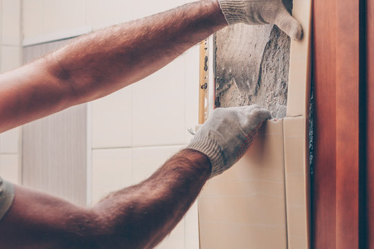 Working with his hands carefully removes old tiles from the wall
