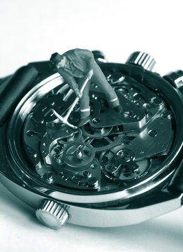small toy worker figurine over vintage watch machinnery: time is money concept