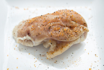 a seasoned raw chicken breast is shown on a white plate