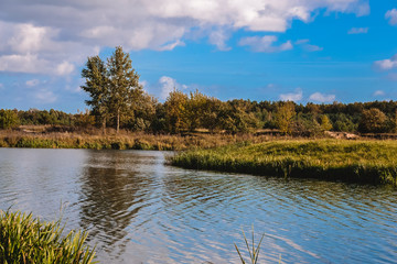 Green field with traces of cars near the city in an autumn day against a background of diverse clouds of sky
