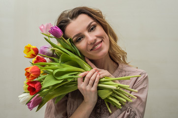 Naklejka premium Young charming girl with a bouquet of flowers - multi-colored tulips