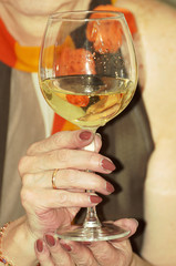 A woman holds a glass of wine in her hand.