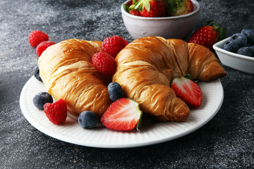 Delicious breakfast with fresh croissants and ripe berries on old marble background
