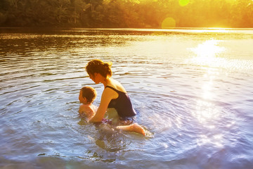 mother teaches a child to swim outdoors. little boy learning to swim. the concept of swim lesson...