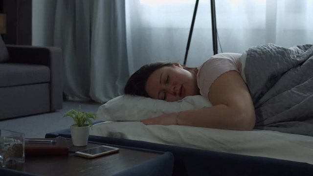 Tired charming plus size brunette woman snoring loudly in the bed in domestic interior. Beautiful middle aged female sleeping in her bedroom and snoring.