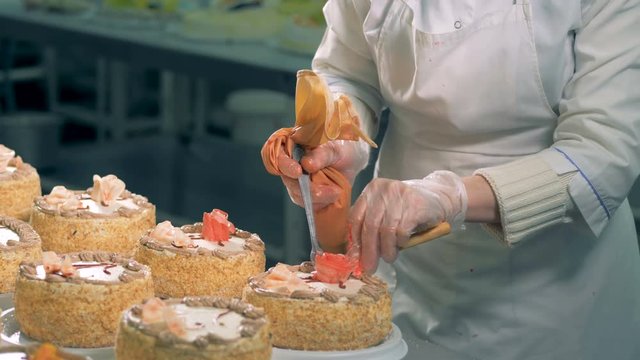 Confectioner puts a creamy rose on a cake.