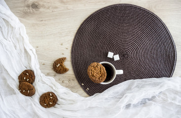 on a wooden table on a white and dark round napkin lie oatmeal cookies Sunflower seeds are a glass...