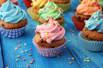 Tasty cupcakes on wooden background. Birthday cupcake in rainbow colors