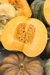 Big Colorful Beautiful Dark Orange and Green Pumpkins Whole and Halved. Dent Texture Seeds. Farmers Market. Thanksgiving Harvest Fall. Organic Produce. Authentic Atmosphere Travel Lifestyle.