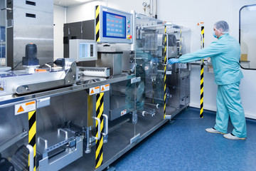 Pharmacy industry factory man worker in protective clothing in sterile working conditions operating...