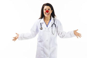 A female doctor with red clown nose and arms out, isolated on white studio background