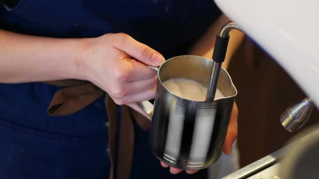 Barista steaming milk for a latte or cappuccino. Seamless cinemagraph video