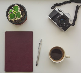 Top view of camera, notepad, pen, flower and cup of coffee