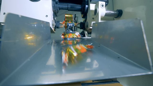 Close up of candies getting wrapped up and falling along the duct