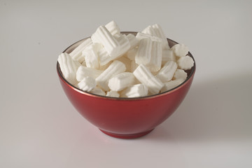 A red plate wit marshmallows on a white background. Close up. Christmas photo. 