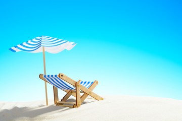 A chaise longue under an umbrella on the sandy beach, sky with copy space